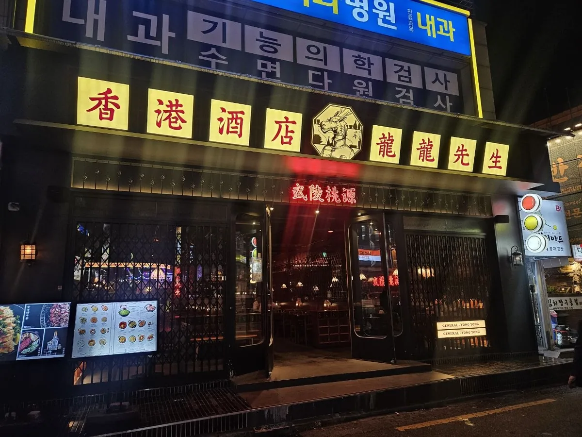 The exterior of Yong Yong Seongsaeng (龍龍先生), a Hong Kong-style restaurant in Seoul, shot at night with its bold Chinese 