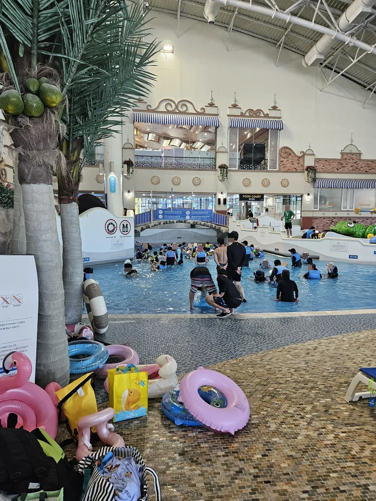The main indoor pool — fake palms, striped awnings, and a whole lot of floaties
