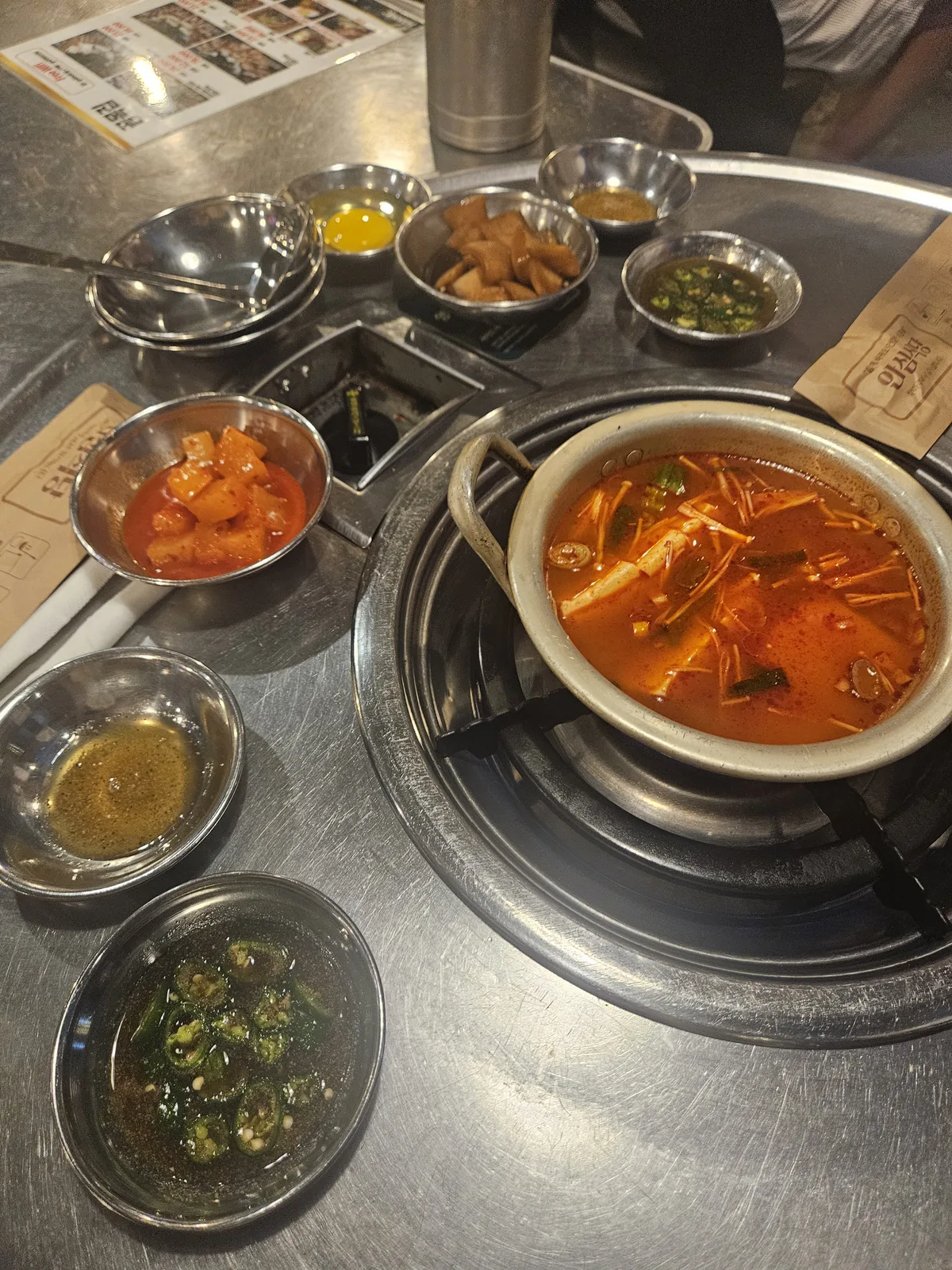 What lands on the table before the meat — soft tofu stew and side dishes